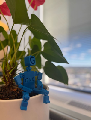 A blue BrandBot displayed beside an office plant