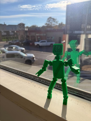 A green BrandBot displayed in an office window